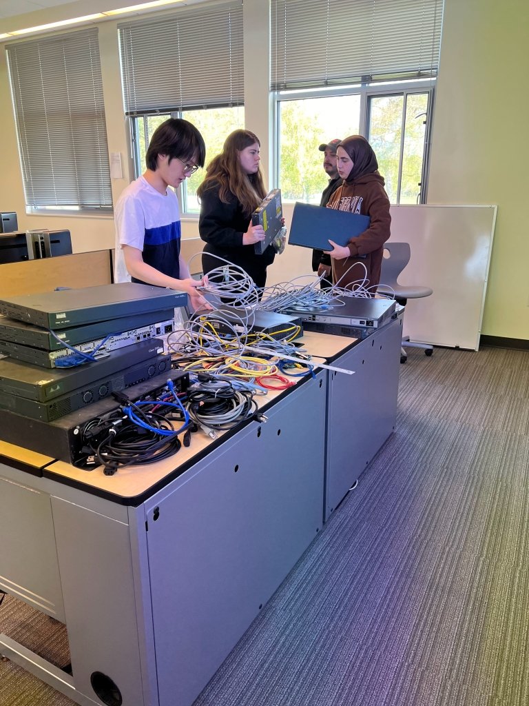 Students sort through computer equipment on a table