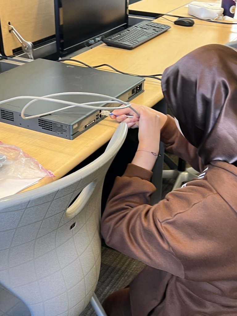 A student plugs a cord into the back of a device
