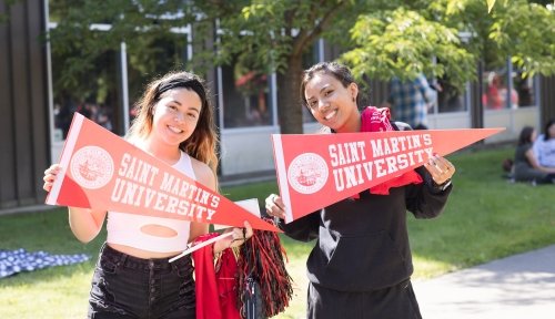 Two students pose outside with SMU pennants at Picnic on the Plaza