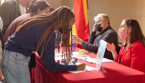 Students sign up at a table where faculty are explaining study abroad programs
