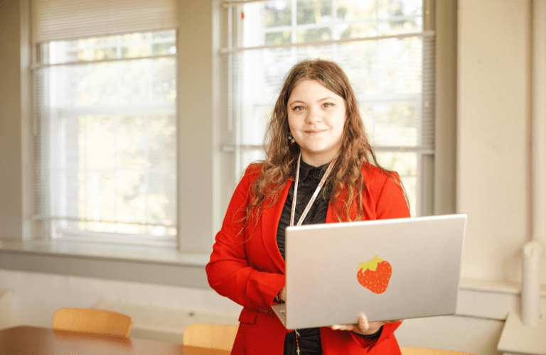Student in business attire holding a laptop