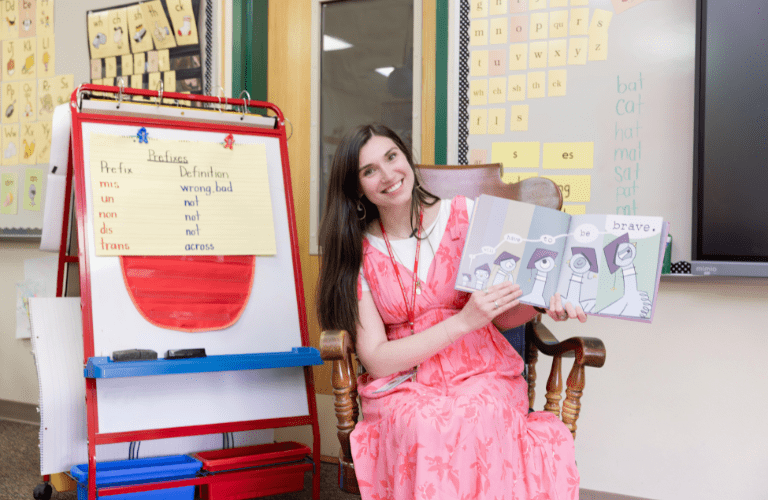 Student holds a picture book at front of elementary classroom