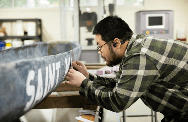 A student fixes letters on a concrete canoe