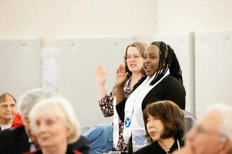 Two students stand and raise their right hands with national honor society stoles