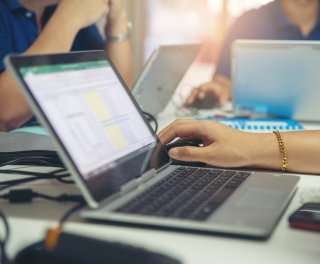 Shows a hand next to a laptop