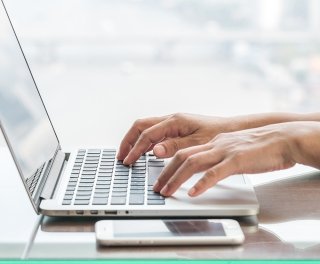 Hands type on a laptop keyboard