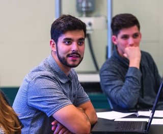 A student engages in class while another looks on.