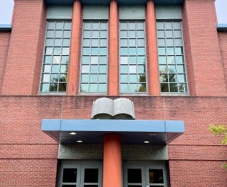 Facade of O'Grady Library, with a focus on the book statue above the doorway.