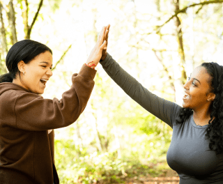 Two students high five outdoors