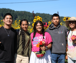 Scholars with arms around each other in front of sunflowers