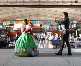 Students in traditional dress perform on stage