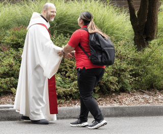 A person in Catholic robes greets a student