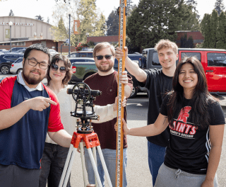 Students work with surveying equipment outside
