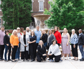 Doctoral cohort standing in front of fountain outside
