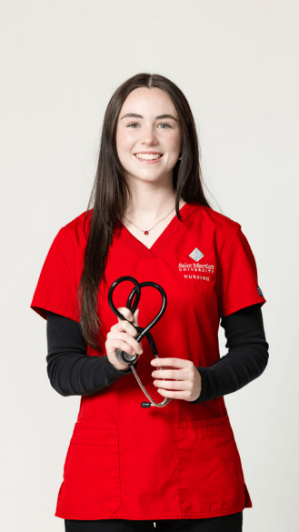 Student in red scrubs holding a stethoscope