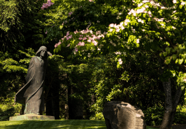 Statue of St. Benedict in a lush spring outdoor setting