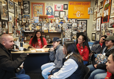 Students listen to a man in a Homeboy Industries office