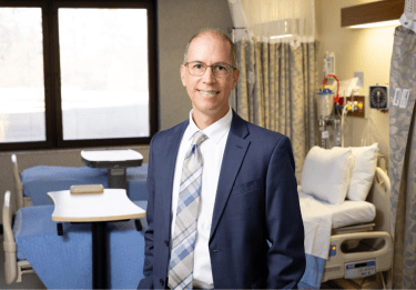 Will Callicoat poses in front of hospital room, with window and bed