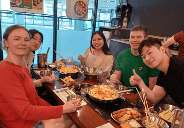 Students sitting around a table filled with food at a restaurant