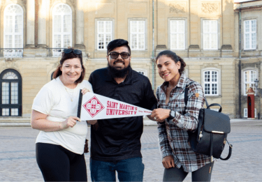 Students hold a Saint Martin's pennant in a European plaza