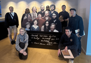 Students and faculty pose with cutout of Microsoft founders