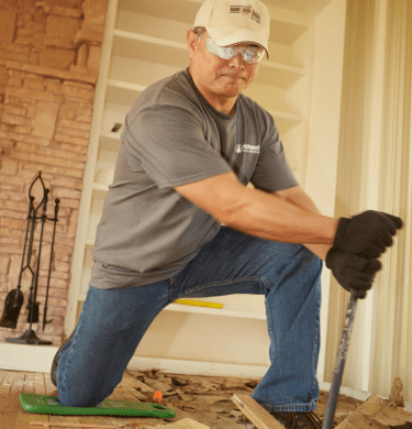 An alum uses a tool to do some construction on the floor in a house