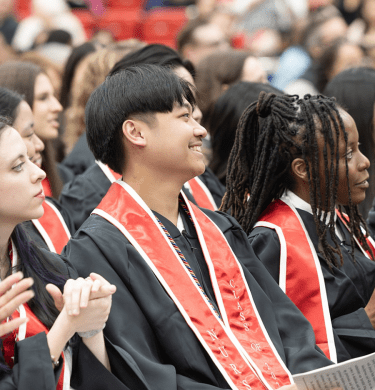 Students in graduation gowns sit in rows