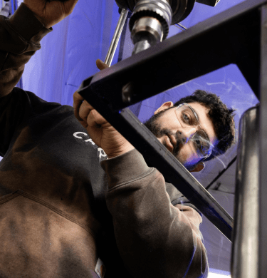 A student in protective eyewear works with machinery