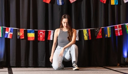 Photo of a international student kneeling on a stage.