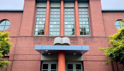 Facade of O'Grady Library, with a focus on the book statue above the doorway.