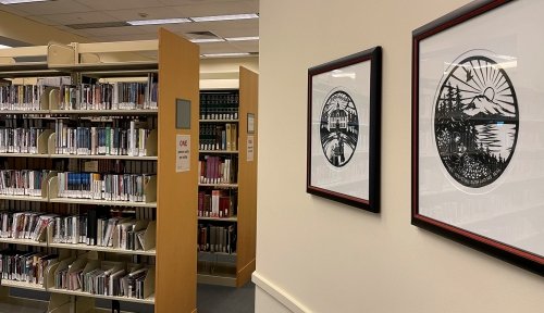 Interior shot of library, showing bookcases to the left and artwork on the walls to the right.