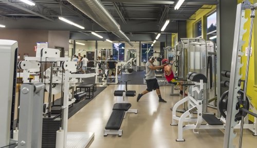 Two students use equipment in the Charneski Rec Center weight room