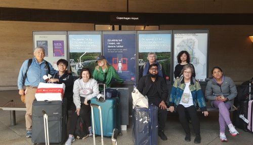 Students and faculty pose at a bus stop at Copenhagen Airport