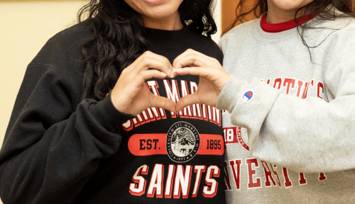 Two students wearing SMU sweatshirts make a heart with their hands