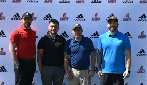 Four people stand in front of a backdrop with Saints Athletics and Adidas logos