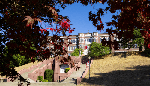 Old Main at the top of the hill, framed by red leaves