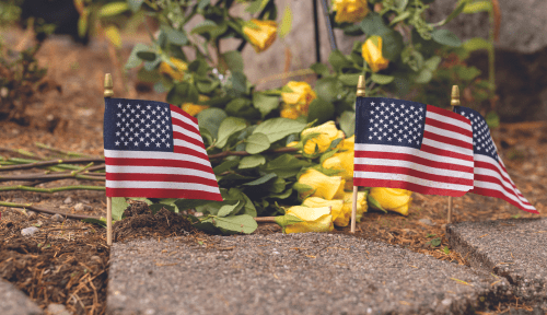 American flags line pavestones in front of yellow roses