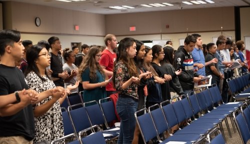 Students stand in rows holding hands