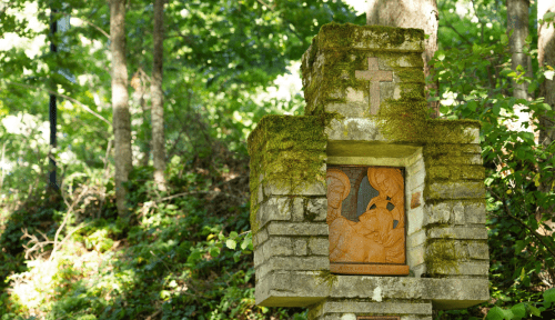 Stone cross with religious imagery in a forest