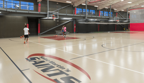 Three people play basketball on a Saints court