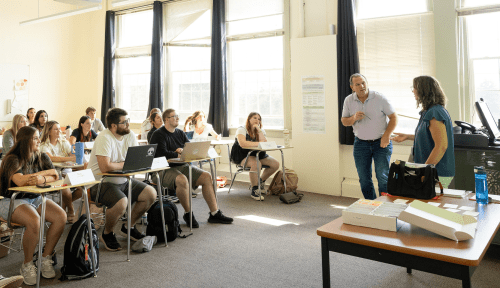 A class sits and listens to professors