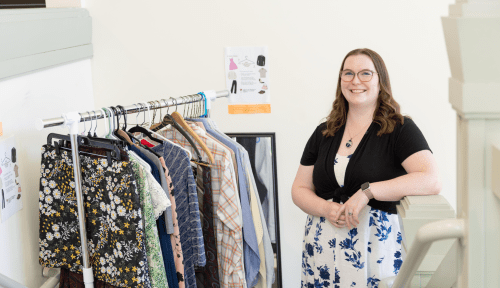 A staff member stands in front of a rack of clothing