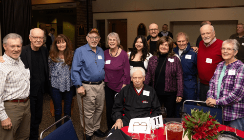 A group of alumni and a monk gather at Homecoming