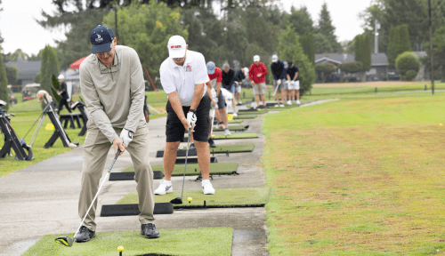 Golfers prepare to swing in a long line on the green