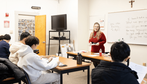 A professor teaches from the front of a class of students