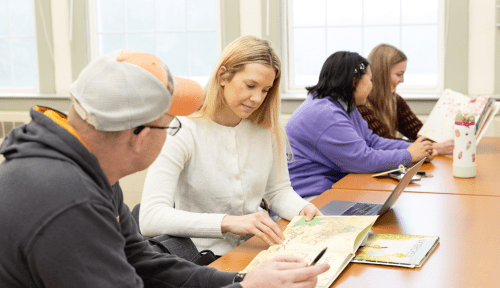 Students looks at elementary-level picture books in class