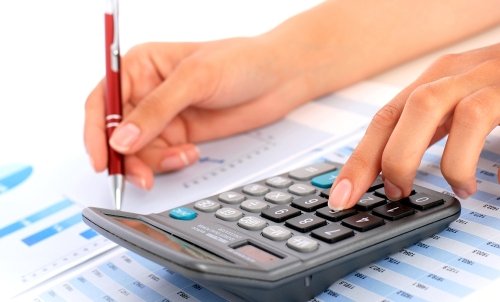 AcademicProgram_Accounting_dreamstime_xxl_30505526.jpg Close up of hands using a calculator and holding a pen to work on a spreadsheet with graphs.