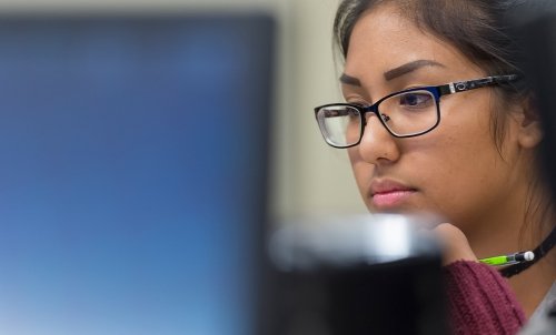 Close up of a student's face from behind the computer she is working intently at.