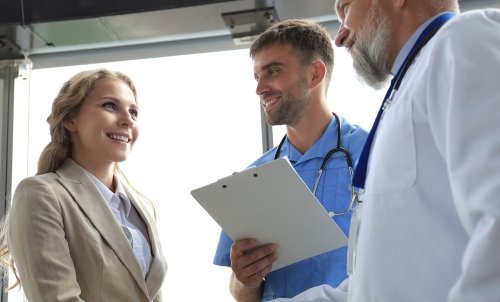 AcademicProgram_HealthCareManagement_dreamstime_xl_179702539.jpg A doctor and a nurse with a clipboard speak to a woman in business clothes.