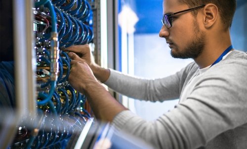 A young man works on a panel of blue wires.